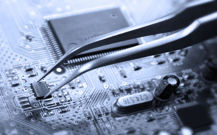 Tweezers picking a chip off a circuit board